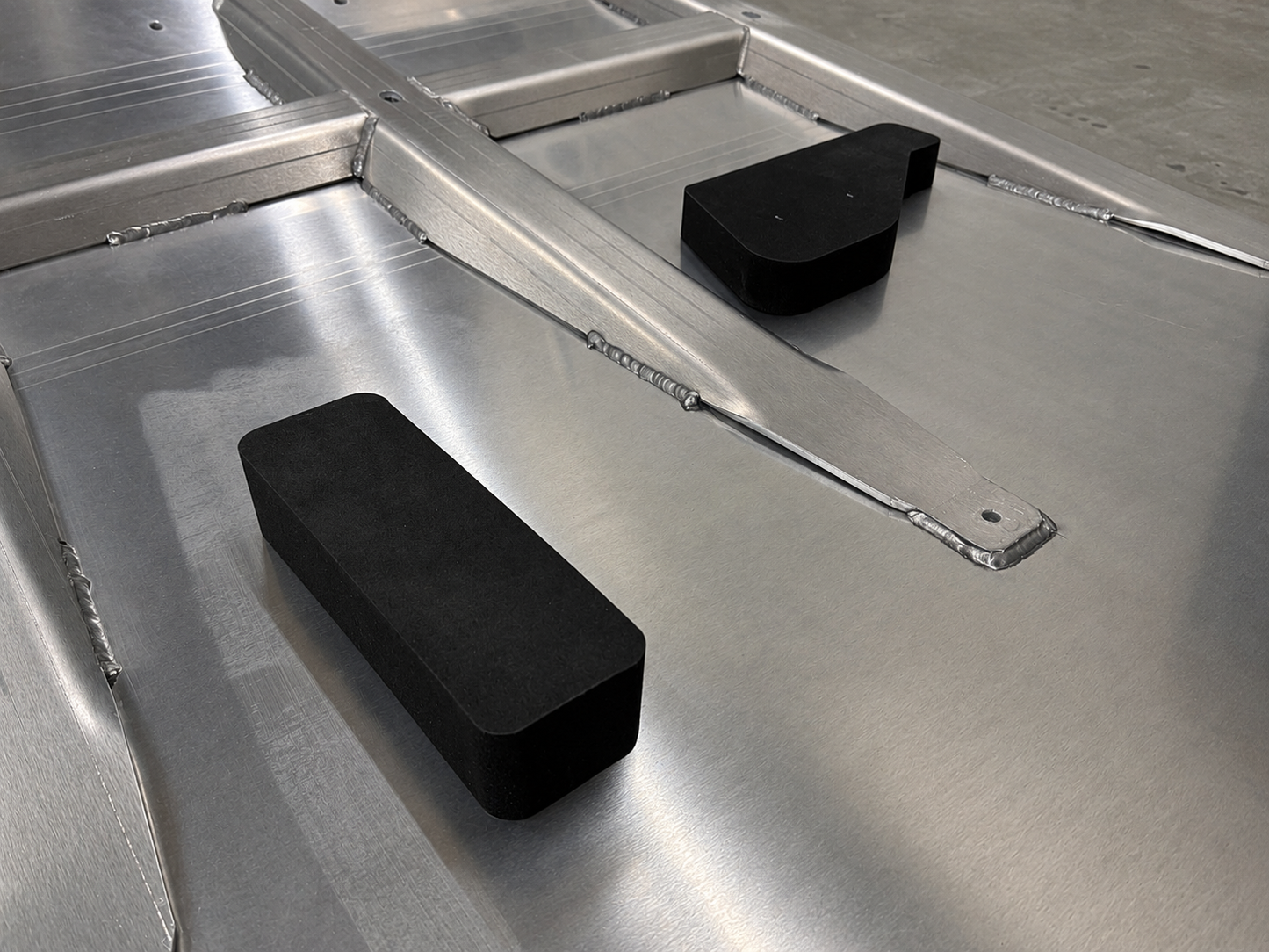 Reinforced aluminium skid plate underside showing welded strengthening ribs with oil sump and gearbox protection foam